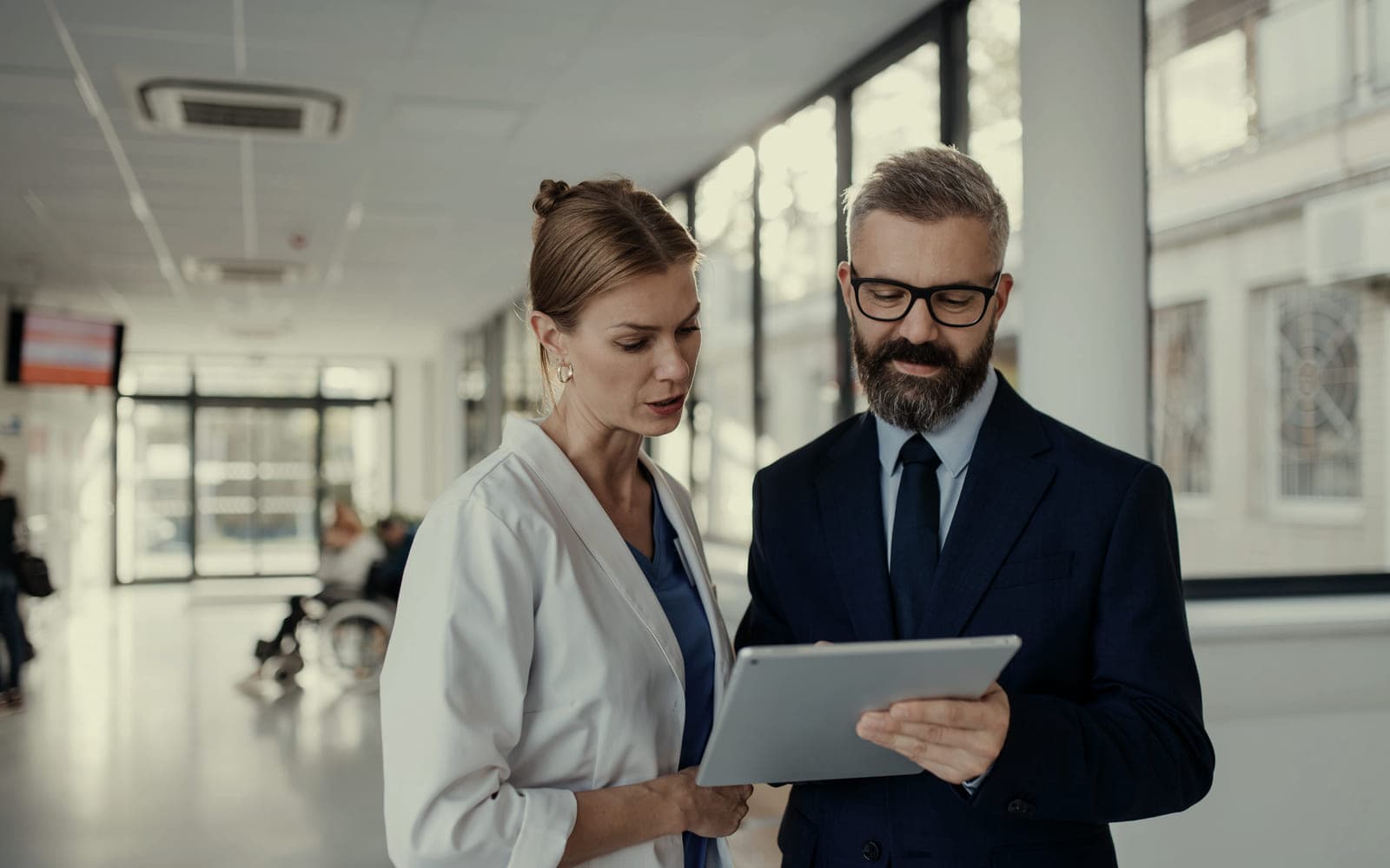 Two people standing together, looking at the same tablet
